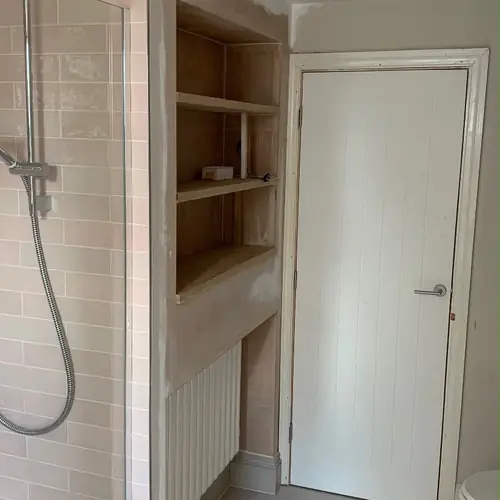 Bathroom with a built-in shelving niche beside a new door