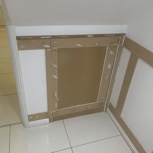 Concealed under-stairs hatch in wall panelling