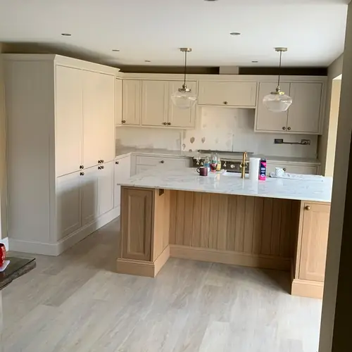 Cream kitchen with an oak island and glass pendant lights
