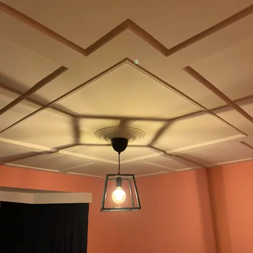 Geometric ceiling panelling around a pendant light