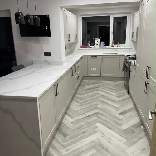 Grey shaker kitchen with marble-effect quartz worktops and herringbone floor