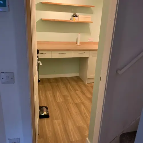 Home office alcove with an oak desk and floating shelves