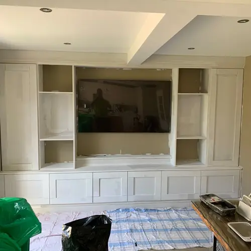 Built-in media wall with open shelving being finished