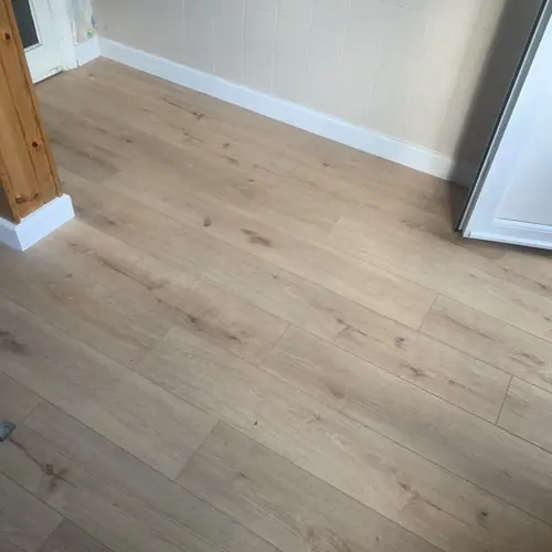 Oak-effect laminate flooring fitted with new white skirting