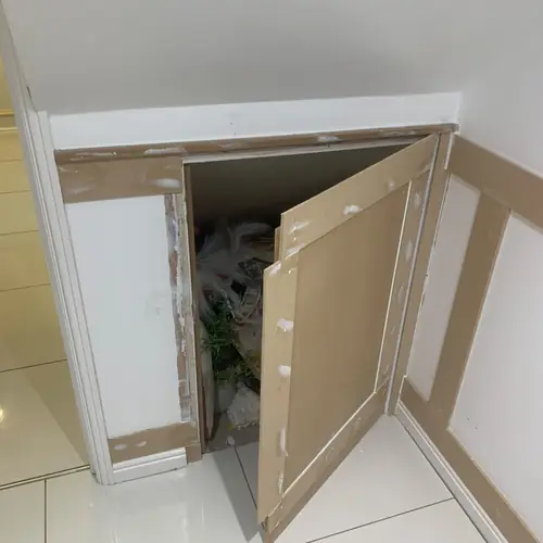 Under-stairs storage hatch built into wall panelling