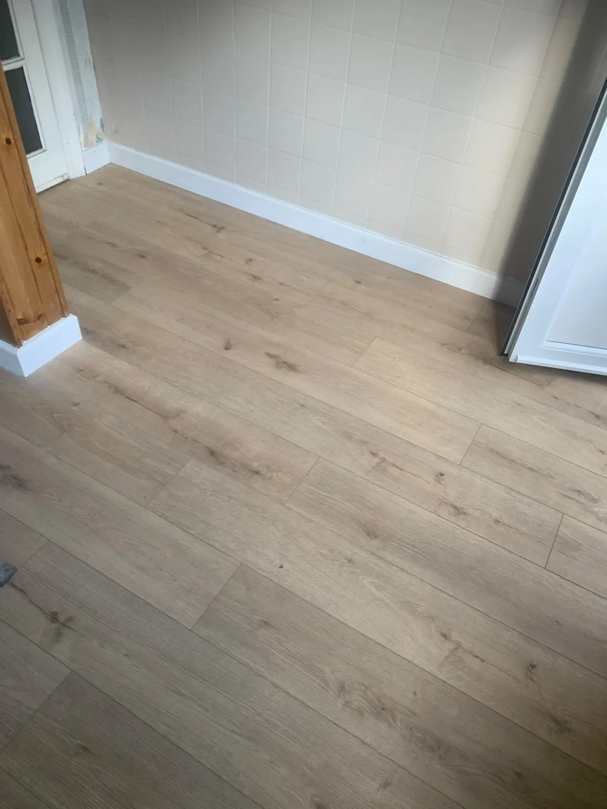 Oak-effect flooring fitted in a bright living room with new skirting