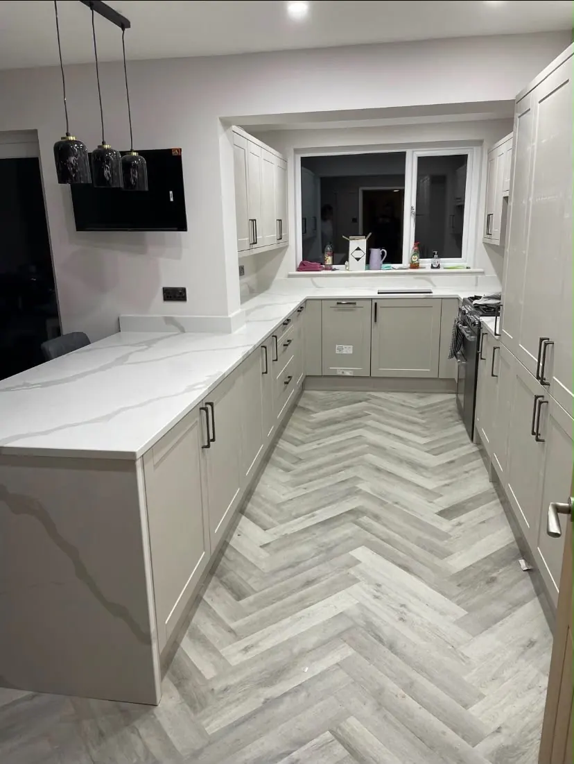 Grey shaker kitchen with marble-effect worktops and herringbone flooring